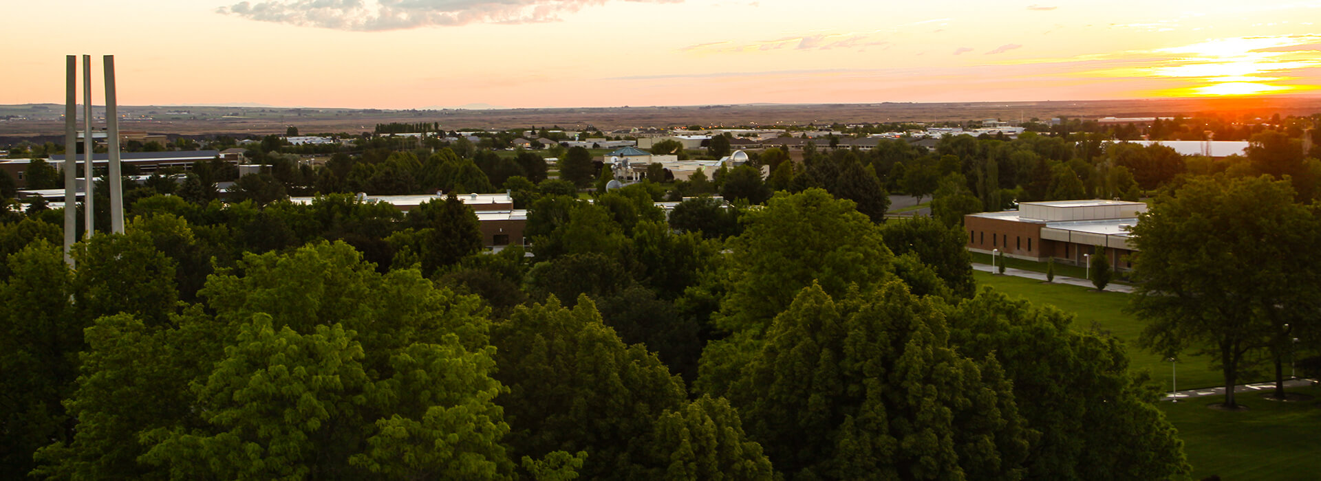 Campus at twightlight with a beautiful sunset in the background barely lighting the buildings of campus in the foreground. 