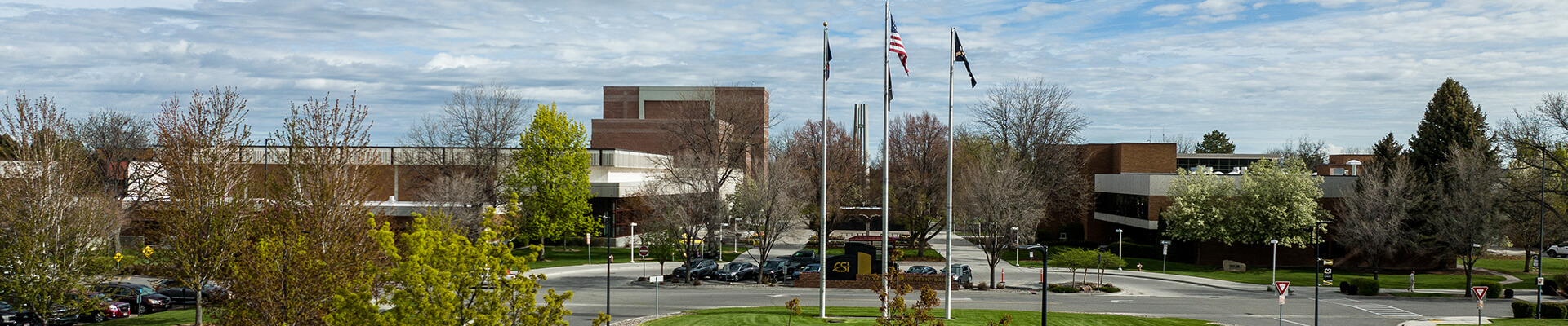 main entrance to the CSI campus showing large brick and glass buildings and large trees